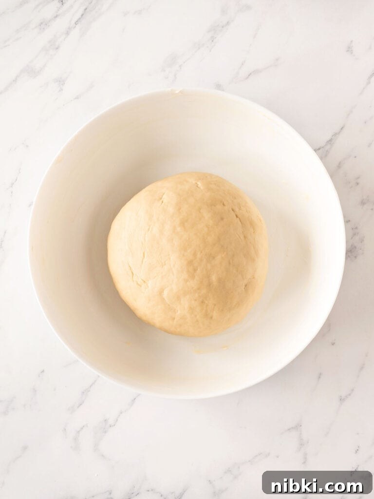 Soft Homemade Yeasted Dinner Rolls 8 White bowl with bread dough. Top view. White marbled surface.