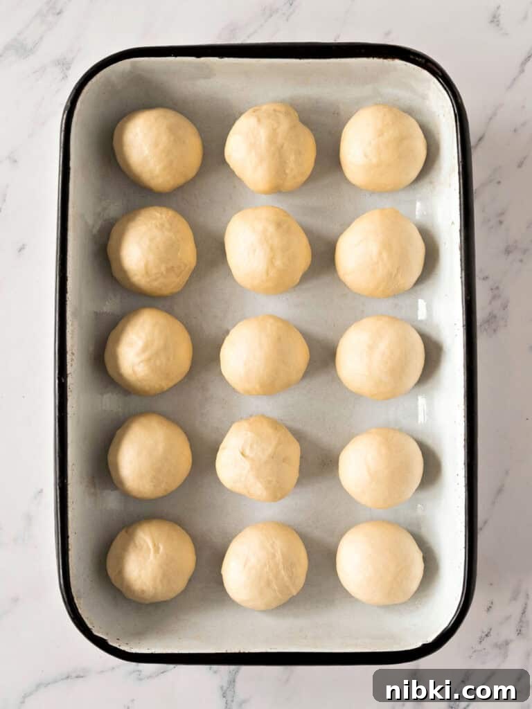 Soft Homemade Yeasted Dinner Rolls 10 Rectangular enameled pan with white bread rolls. White marbled surface. Top view.