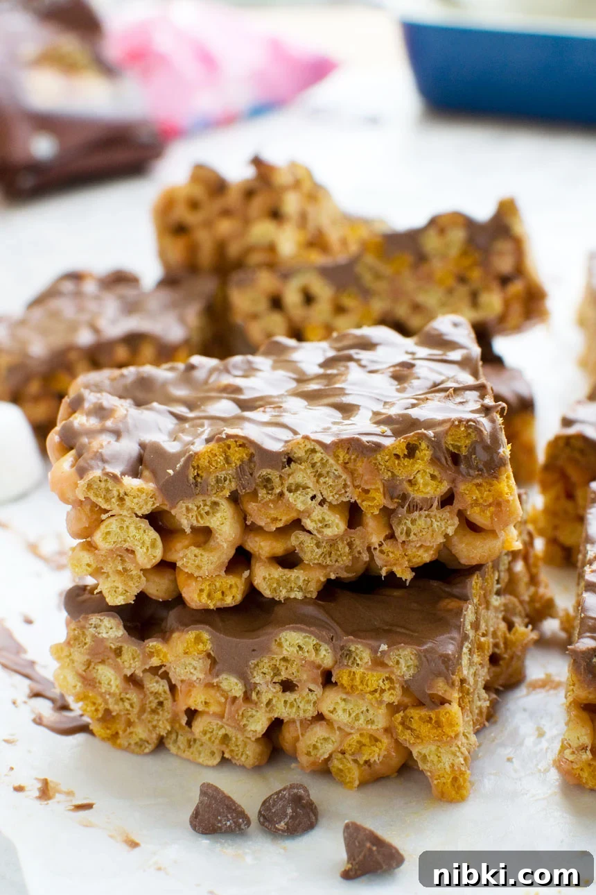 No-Bake 5-Ingredient Peanut Butter Cheerios Bars 2 Two peanut butter cheerio bars stacked on top of each other, with others in the background