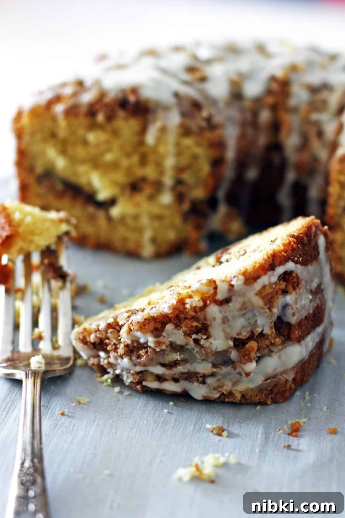 Moist Cinnamon Streusel Coffee Cake Recipe 6 A slice of cinnamon sour cream coffee cake in front of the rest of the cake.