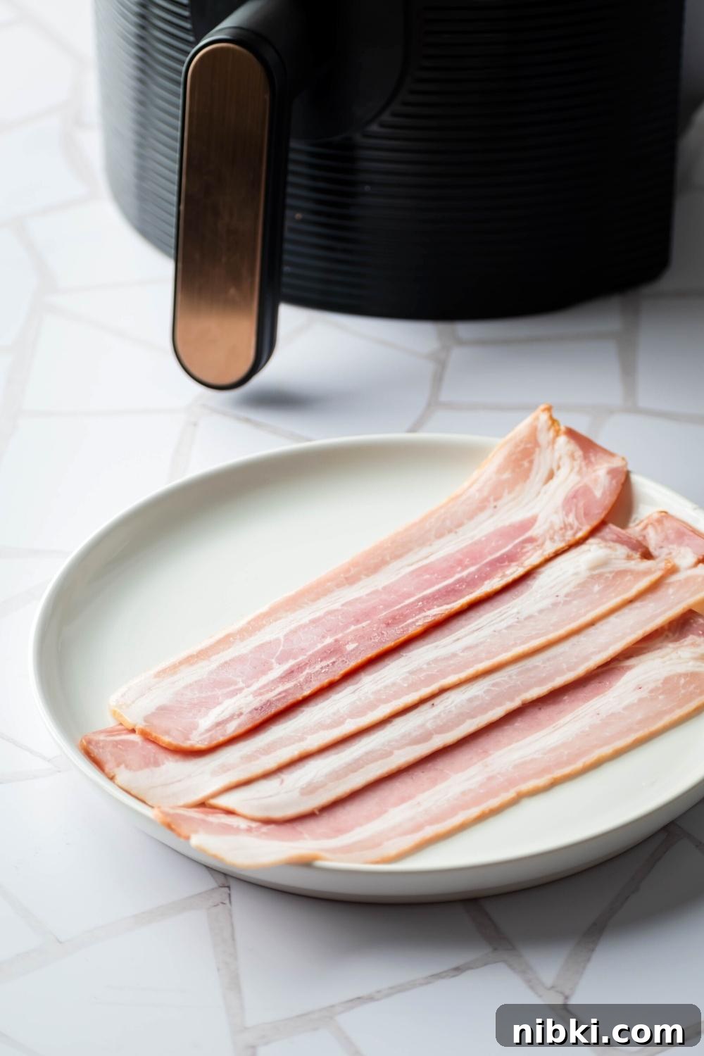 A white plate with four uncooked slices of turkey bacon on it.