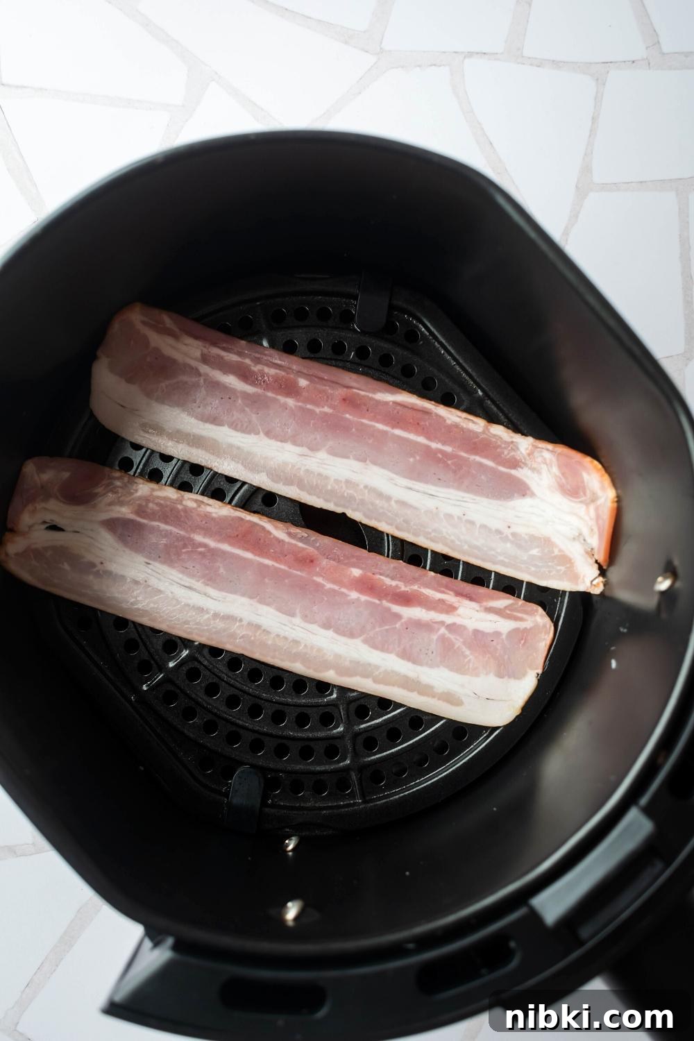 Two uncooked slices of turkey bacon in an air fryer.
