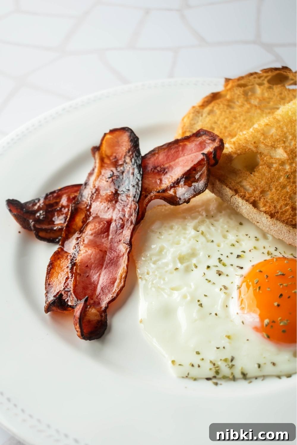 Part of a white plate with toast, an egg, and turkey bacon.