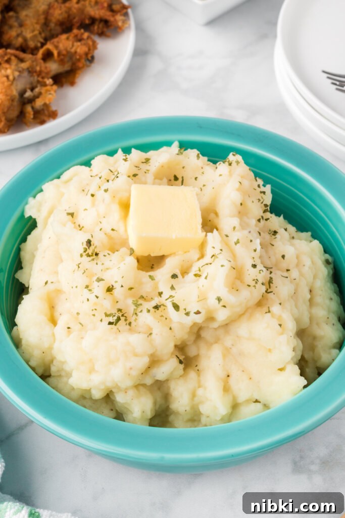 Creamy Garlic Butter Mashed Potatoes Recipe 2 fluffy mashed potatoes topped with butter in an aqua colored bowl