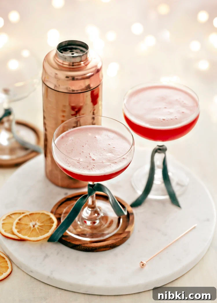 two coupe glasses filled with cranberry orange whiskey sour