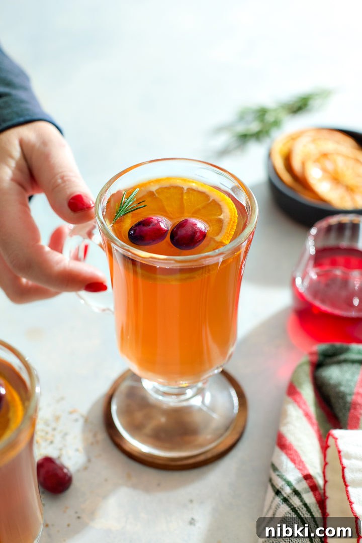A woman's hand reaching for a whiskey and tea hot toddy.