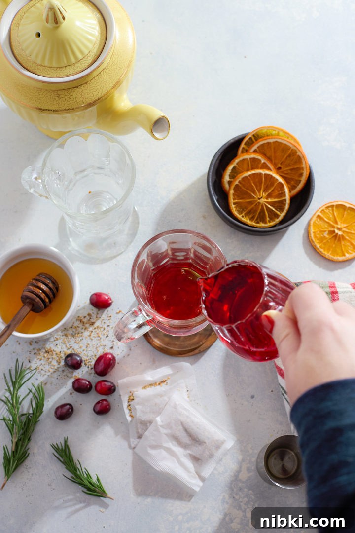 Adding cranberry syrup to a hot toddy.