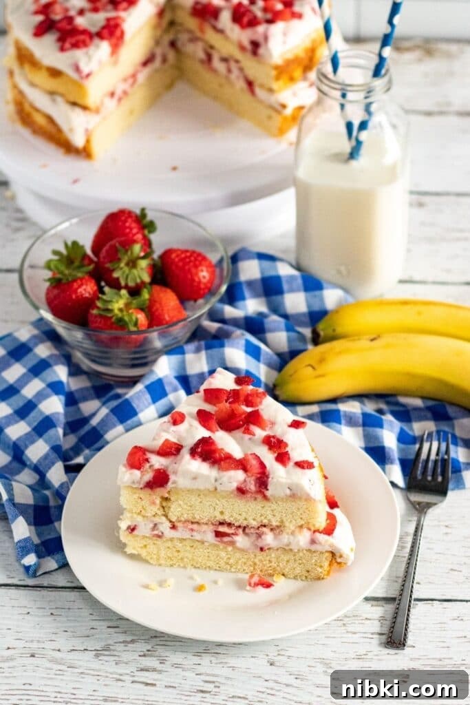 slice of strawberry cake on plate with layered cake behind it