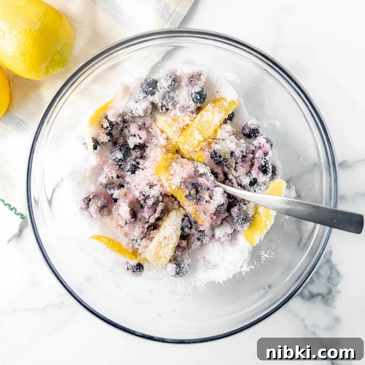 Homemade Blueberry Lemonade Recipe for a Refreshing Summer 3 Berries and lemon peel tossed in sugar in a bowl.