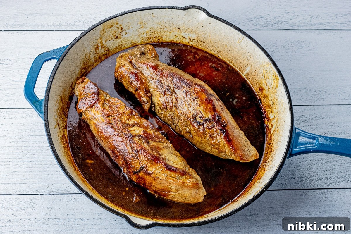 two pork tenderloins in a cast iron pan with maple glaze