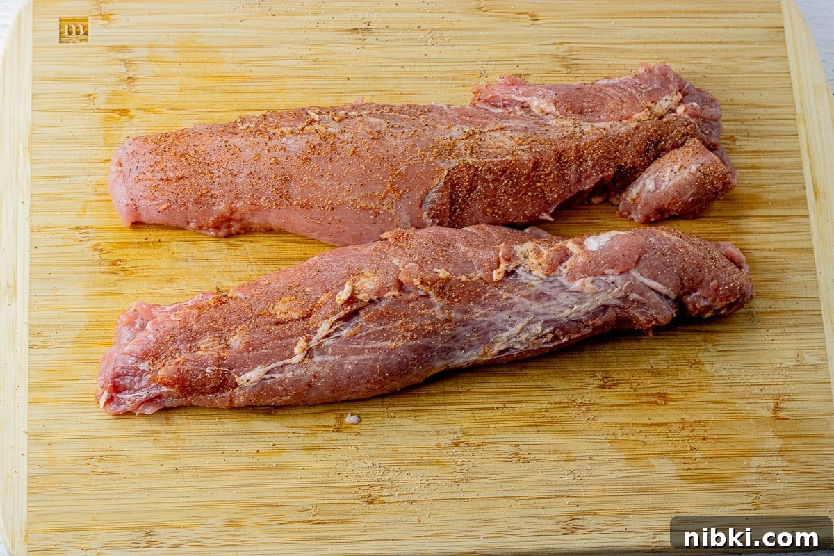 two pork tenderloins uncooked, on a wooden cutting board