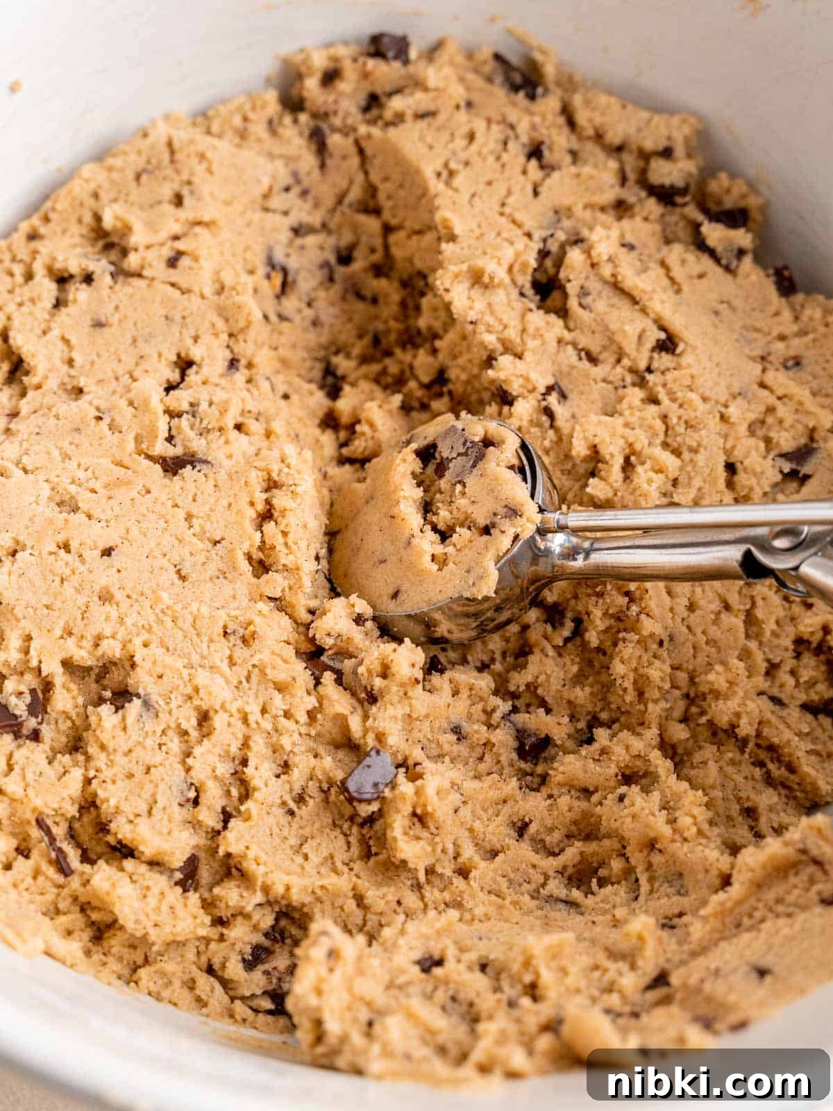 Browned Butter Snickerdoodles with Cinnamon Sugar 7 Cookie dough with cinnamon, cardamom, browned butter and chocolate toffee bits in a bowl with a cookie scoop.