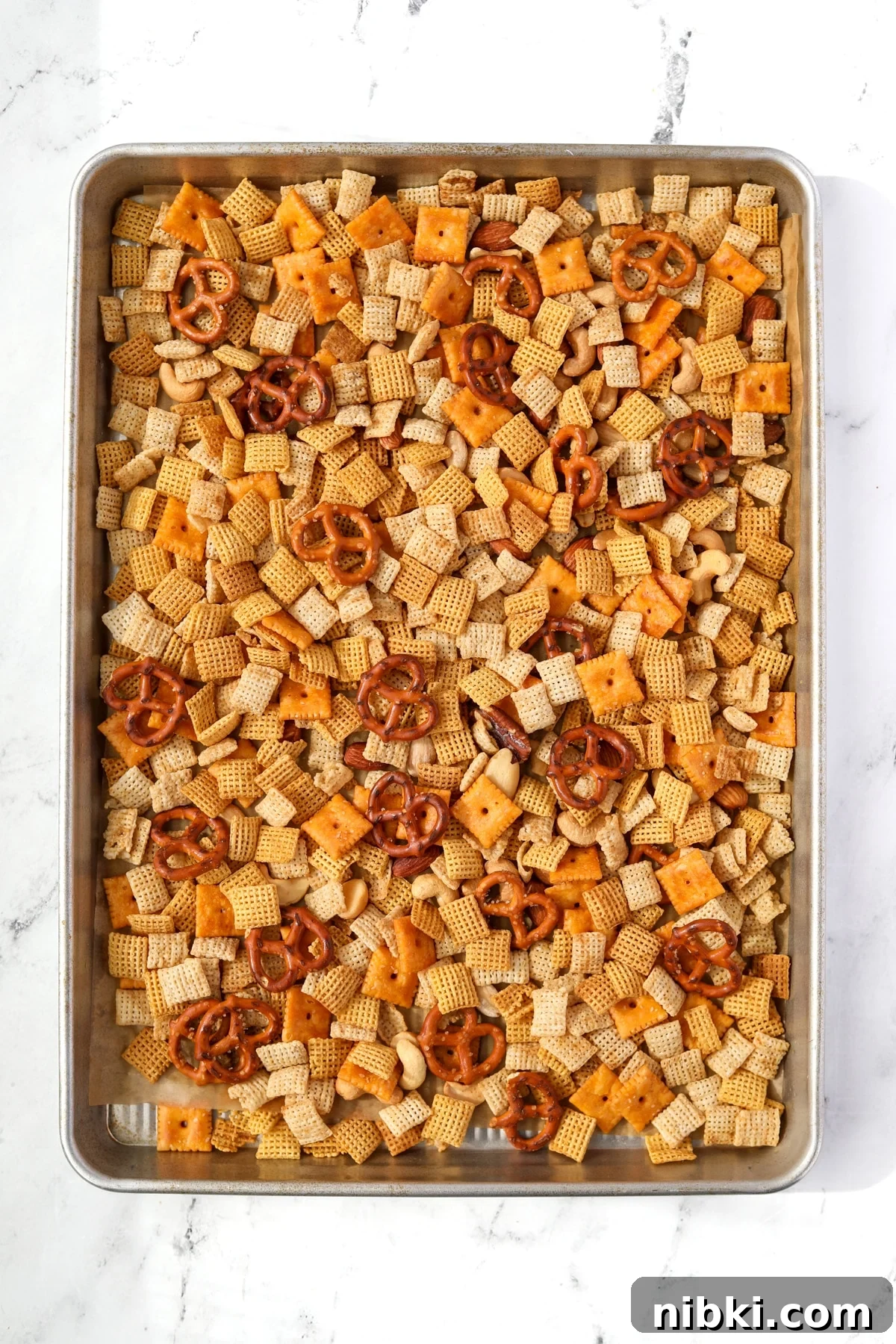 Homemade Chex Mix: Savory Snack Mix Recipe 8 A baking sheet filled with snack mix with pretzels, cereal, and crackers.