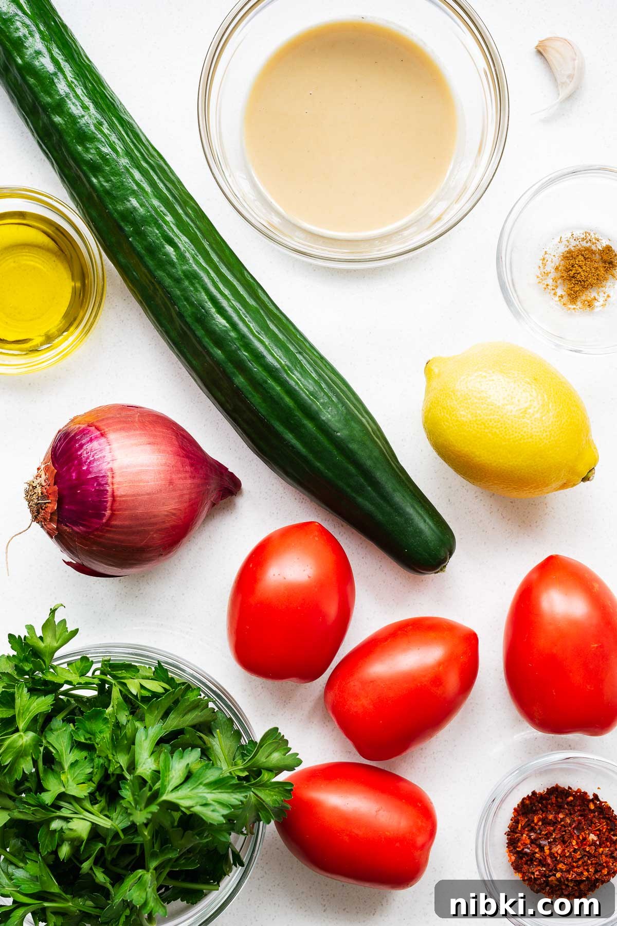 Tahini salad ingredients arranged on a kitchen counter viewed from above.