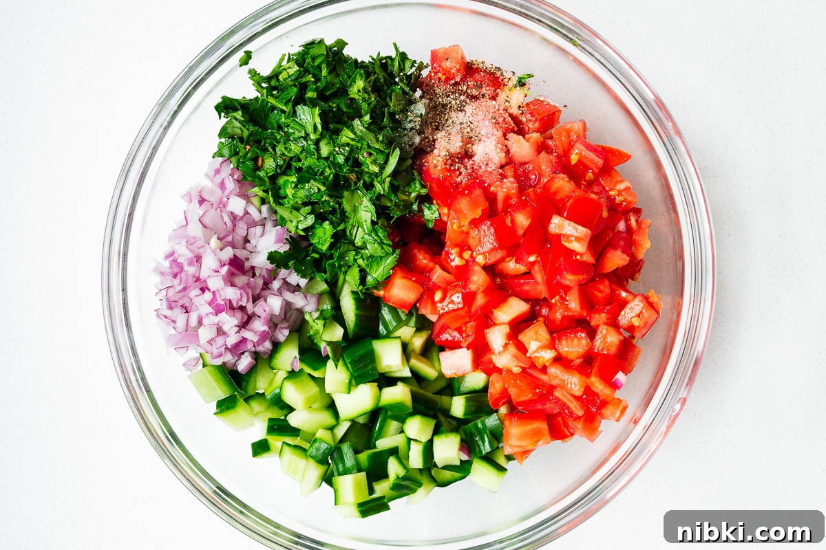 Cubed israeli salad ingredients in a mixing bowl.