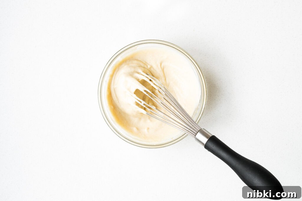 Tahini sauce for Israeli salad in a small mixing bowl with a whisk.