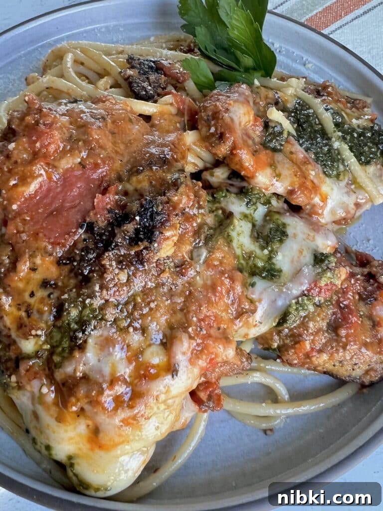 Skillet Chicken Parmesan with Pesto 13 Chicken parmesan with pesto on dinner plate with parsley garnish.