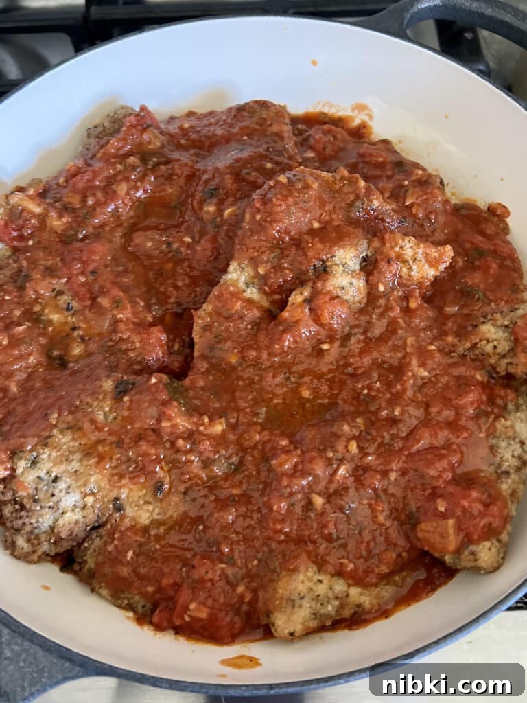 Skillet Chicken Parmesan with Pesto 7 Marinara sauce over chicken cutlets in pan.