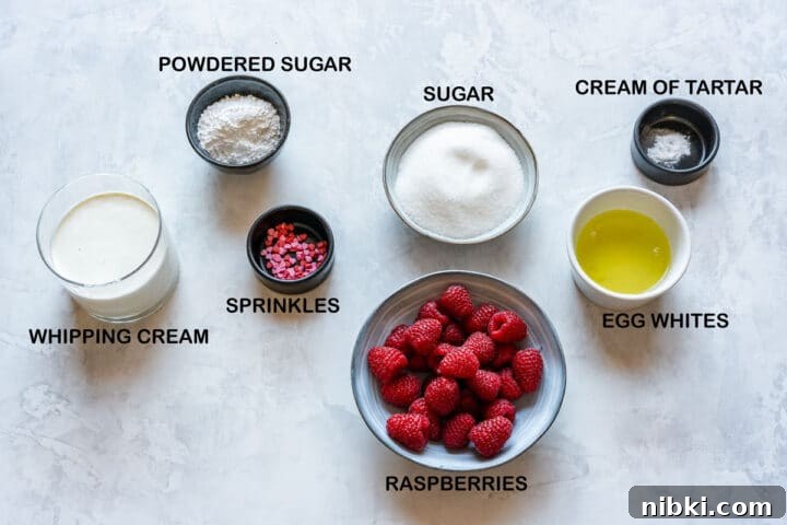 Ingredients laid out for pavlova hearts: egg whites, sugar, cream of tartar, raspberries, whipping cream, powdered sugar, sprinkles.