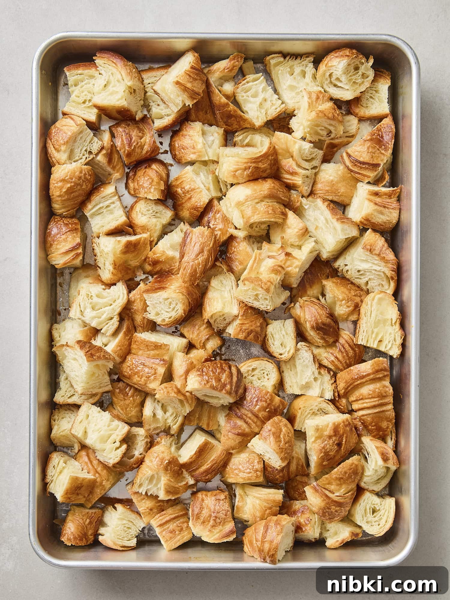 Caramelized Onion and Croissant Stuffing Recipe 8 Toasted croissant torn into pieces on a baking pan.