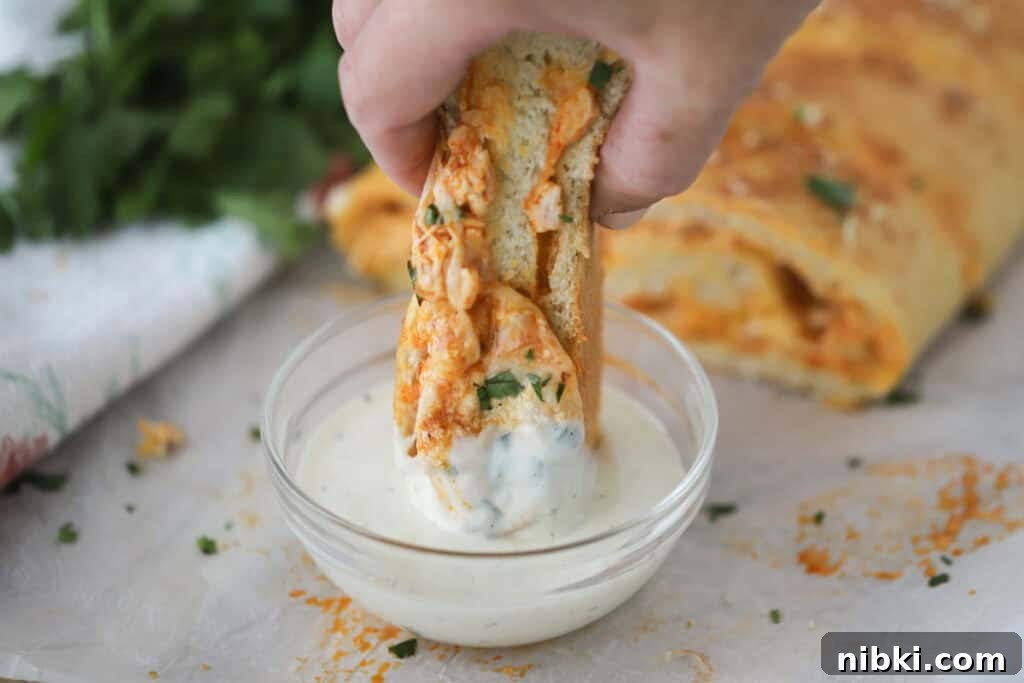 A hand dipping chicken Stromboli into ranch dressing.
