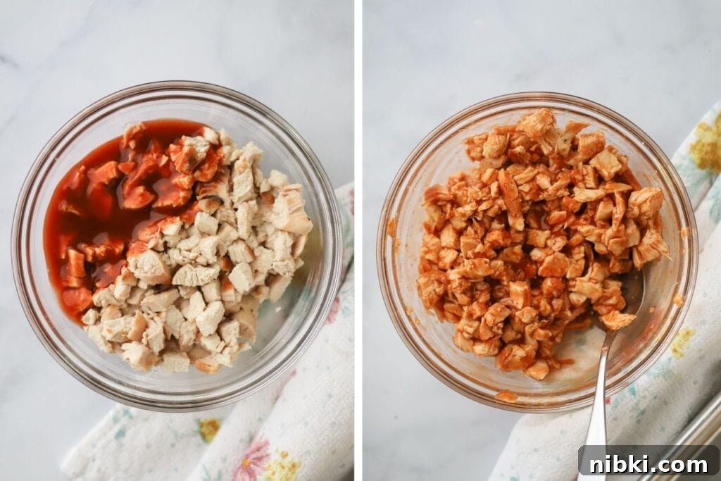 Diced chicken in a glass bowl tossed in buffalo sauce.