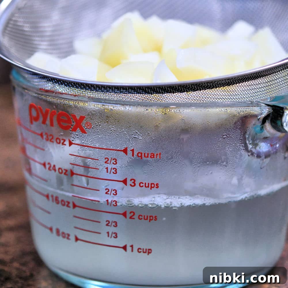 Potato Dinner Rolls: Bread Machine, Hand, or Mixer 4 cooked cubed potatoes in a strainer over a glass measuring cup to catch the cooking water