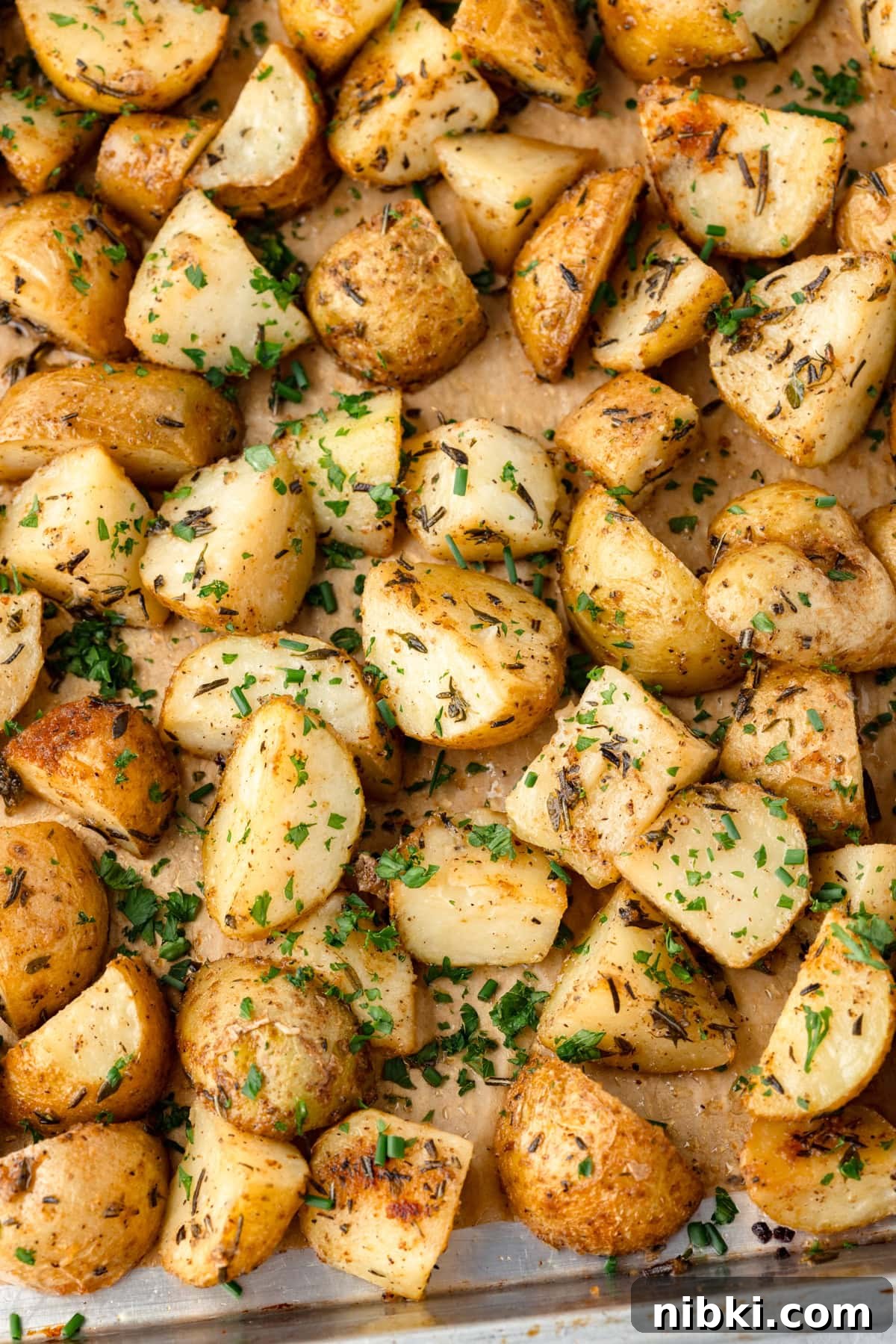 Herb roasted potatoes sprinkled with fresh chopped herbs on a baking sheet.