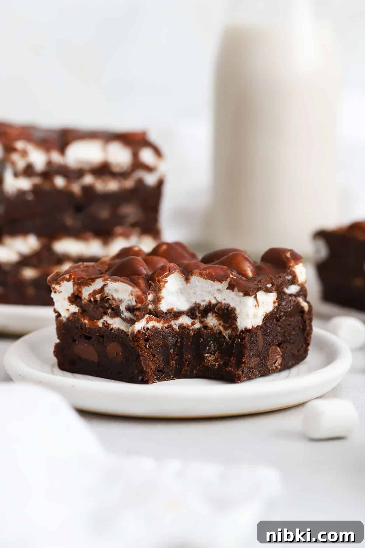 a gluten-free marshmallow brownie on a plate with a bite taken out of it