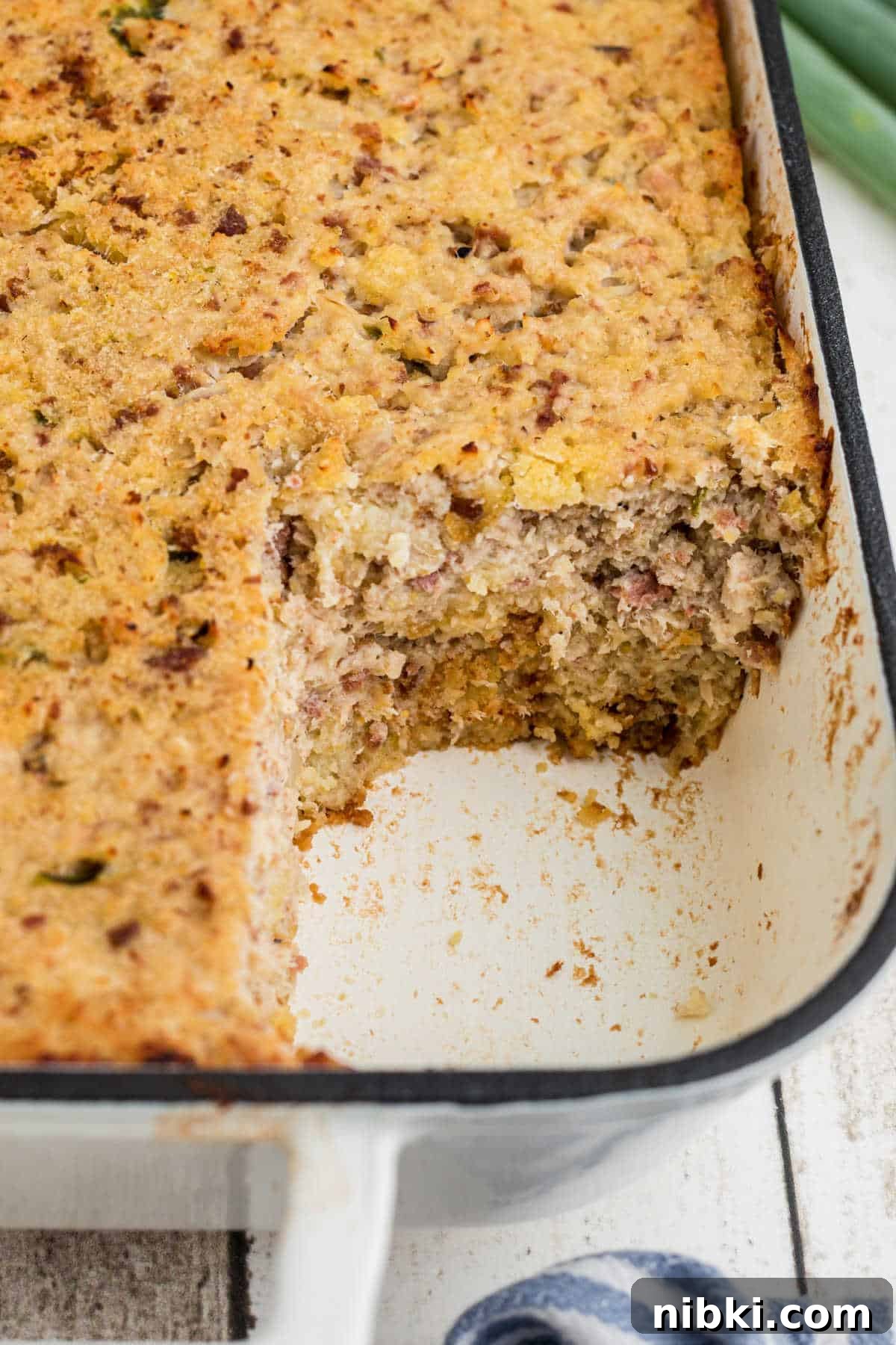 Authentic Cajun Cornbread Dressing Recipe 4 View of the side of a dish with a cornbread dressing in it, with the corner missing.