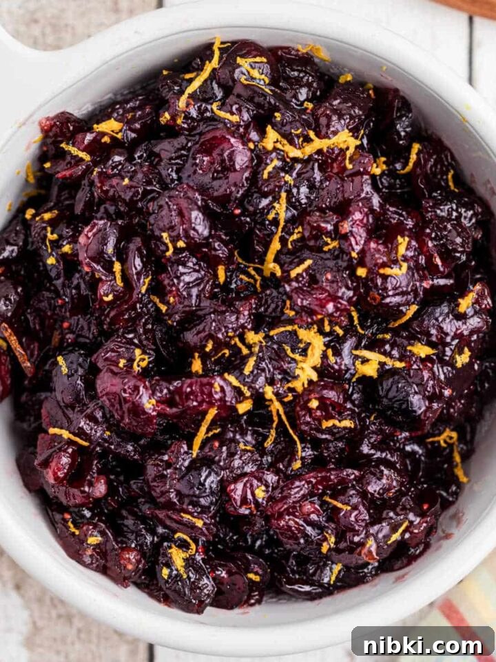 close up overhead image of a bowl of dried cranberry sauce with some orange zest sprinkled on top.