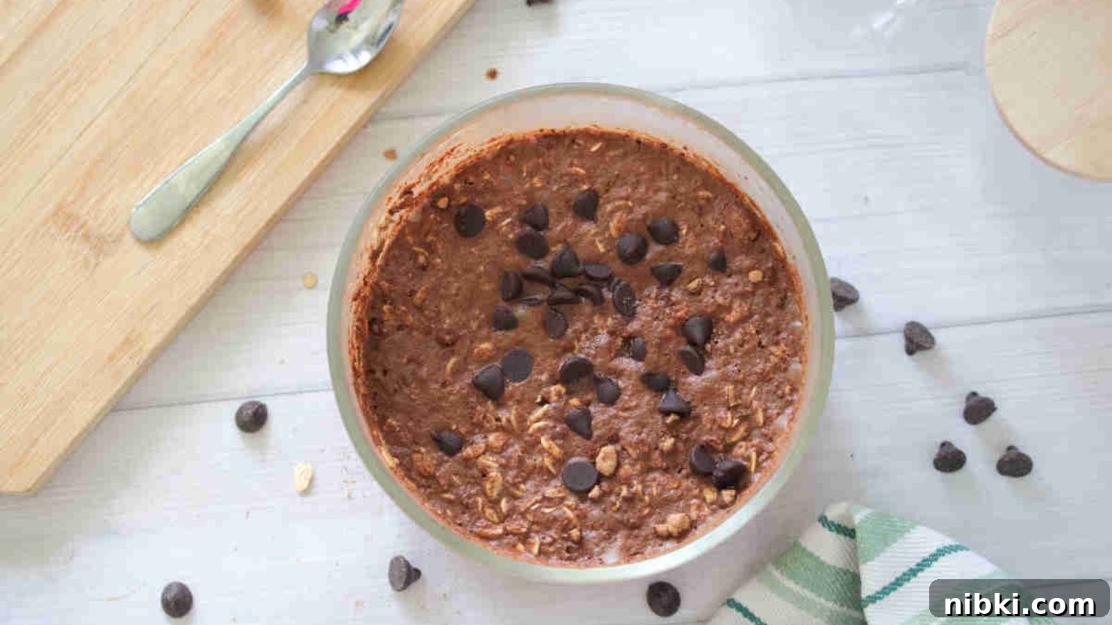 Dairy-Free High-Protein Chocolate Overnight Oats 8 Large bowl with chocolate protein overnight oats topped with chocolate chips and a cutting board and chocolate chips around it.