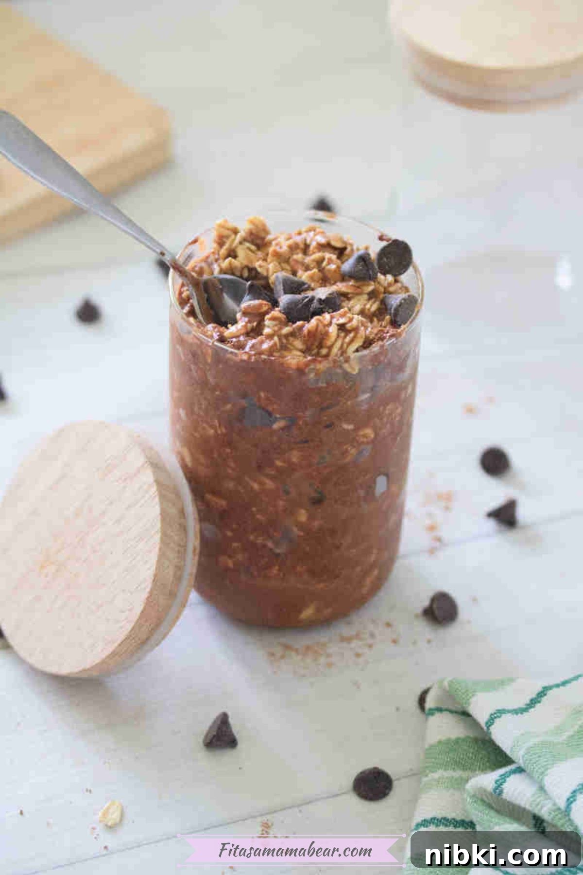 Dairy-Free High-Protein Chocolate Overnight Oats 7 Small jar with chocolate protein overnight oats topped with chocolate chips and a lid beside it.