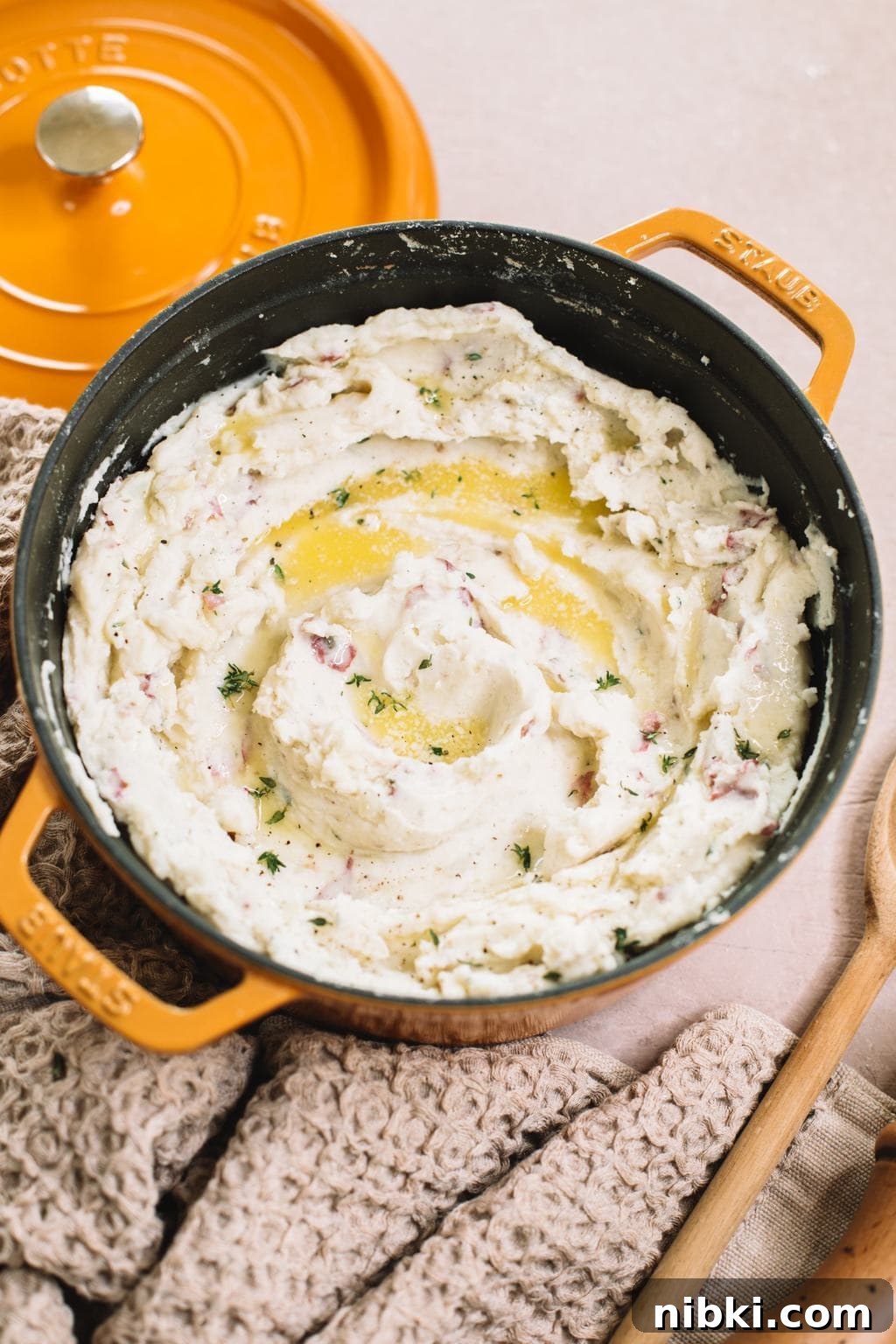 easy garlic mashed red potatoes in yellow dutch oven with melted butter on top