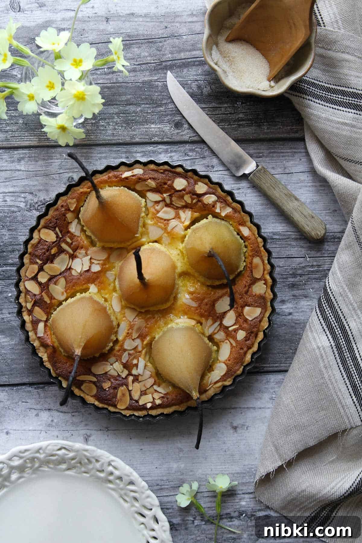 Poached Pear and Almond Tart Recipe 4 An overhead view of the round cake with five whole pears standing up in it.