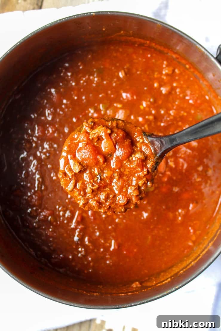 Homestyle Cheesy Chili Mac with Ground Beef and Pasta 5 Spoonful of chili above pot.