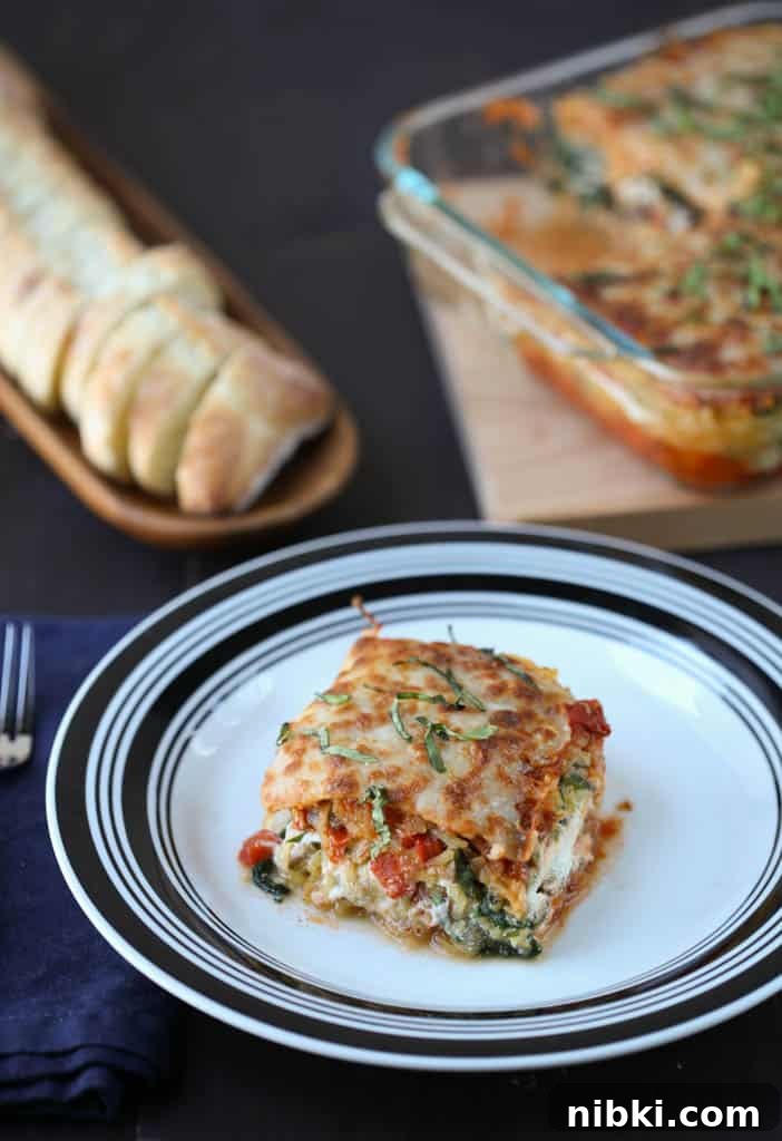 Spaghetti Squash Lasagna Recipe 2 piece of spaghetti squash lasagna on a black and white plate with a whole lasagna and sliced bread in the background.