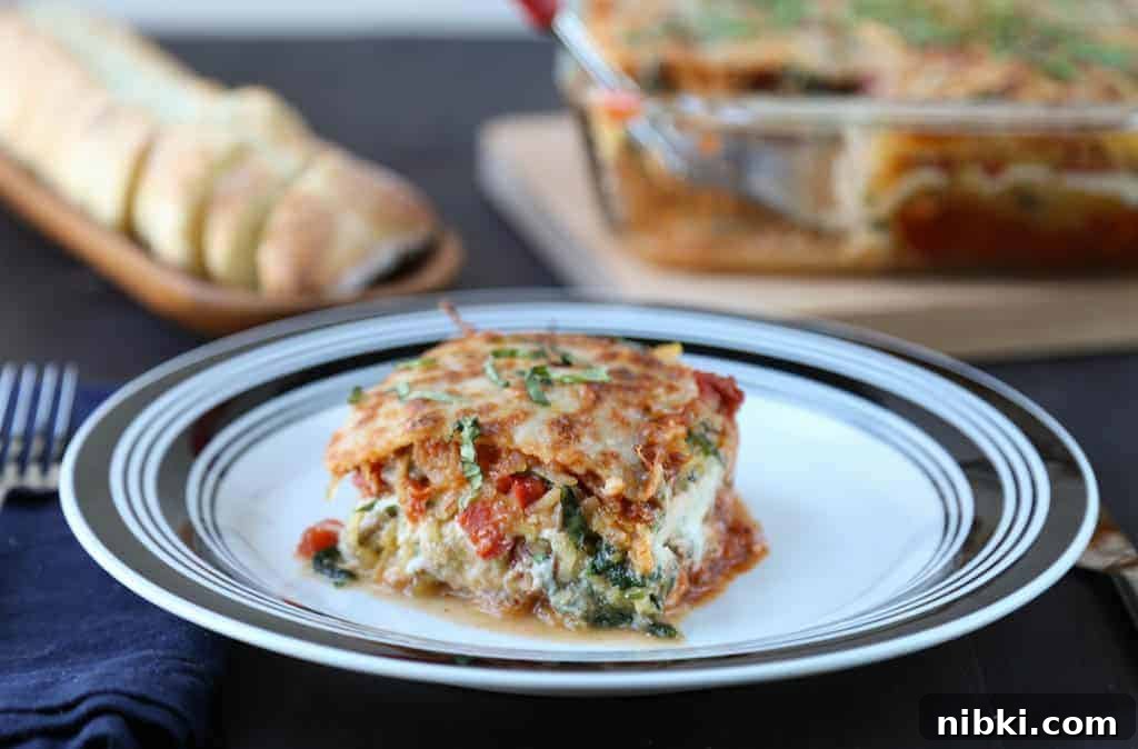Spaghetti Squash Lasagna Recipe 3 piece of spaghetti squash lasagna on a black and white plate with a whole lasagna and sliced bread in the background.