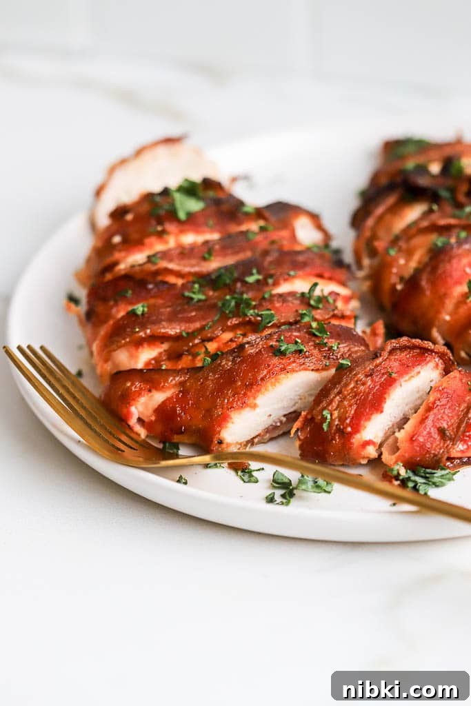 Air Fryer Bacon-Wrapped Chicken Breast: Crispy and Juicy 3 bacon wrapped chicken breast on white plate with golf fork