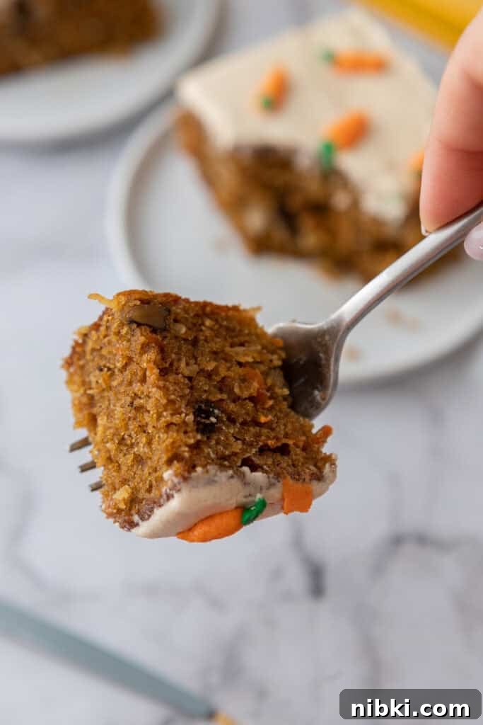 Moist Carrot Sheet Cake Recipe (9x13 Pan) 5 Fork lifting a bite of moist carrot cake sheet cake with frosting