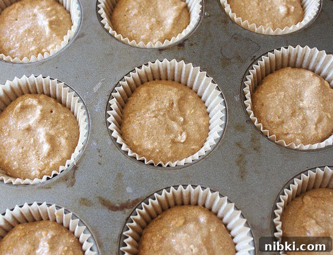 Moist Buckwheat Pumpkin Muffins Recipe 5 Unbaked muffin batter in paper muffin cups in a tray.