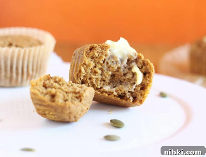 Moist Buckwheat Pumpkin Muffins Recipe 6 Muffin torn in half on a white plate with raw pumpkin seeds.