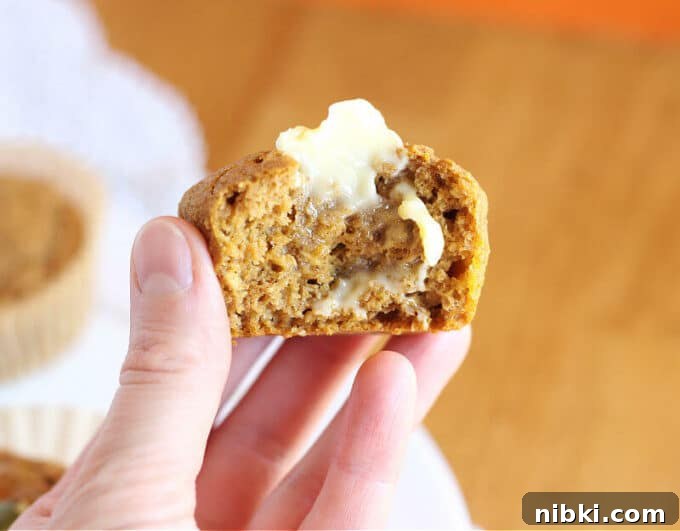 Moist Buckwheat Pumpkin Muffins Recipe 7 Hand holding half of a muffin spread with butter.